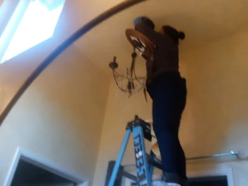 Electrician installing a chandelier in a Laurel Hill residence